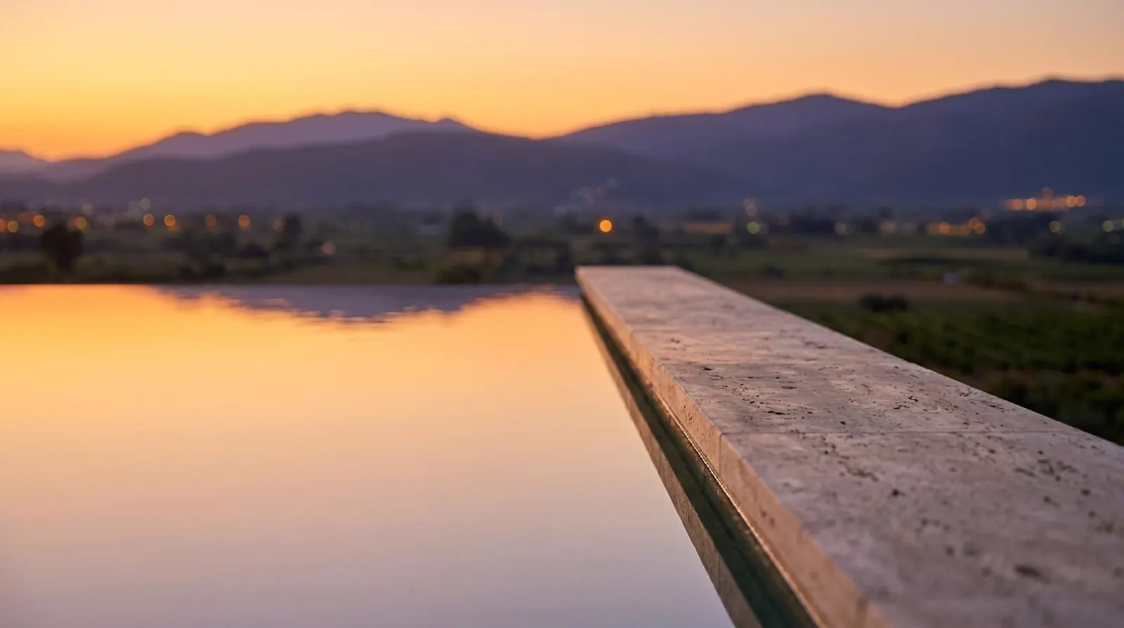 El cantell de la piscina infinita reflectint el cel d'ambre.